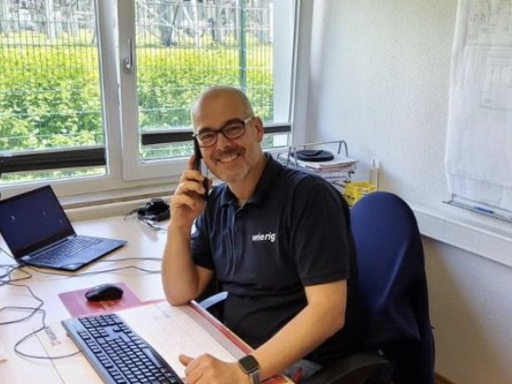 Bauleiter am Schreibtisch telefonierend.